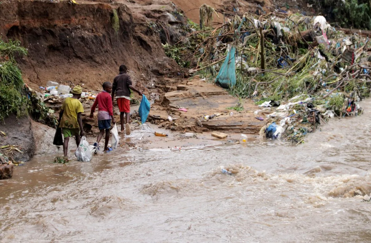 Young boys carry plastic as they look for items to salvage from the Nasolo river in Ndirande township in Blantyre, Malawi, on March 15, 2023. (Eldson Chagara/Reuters)