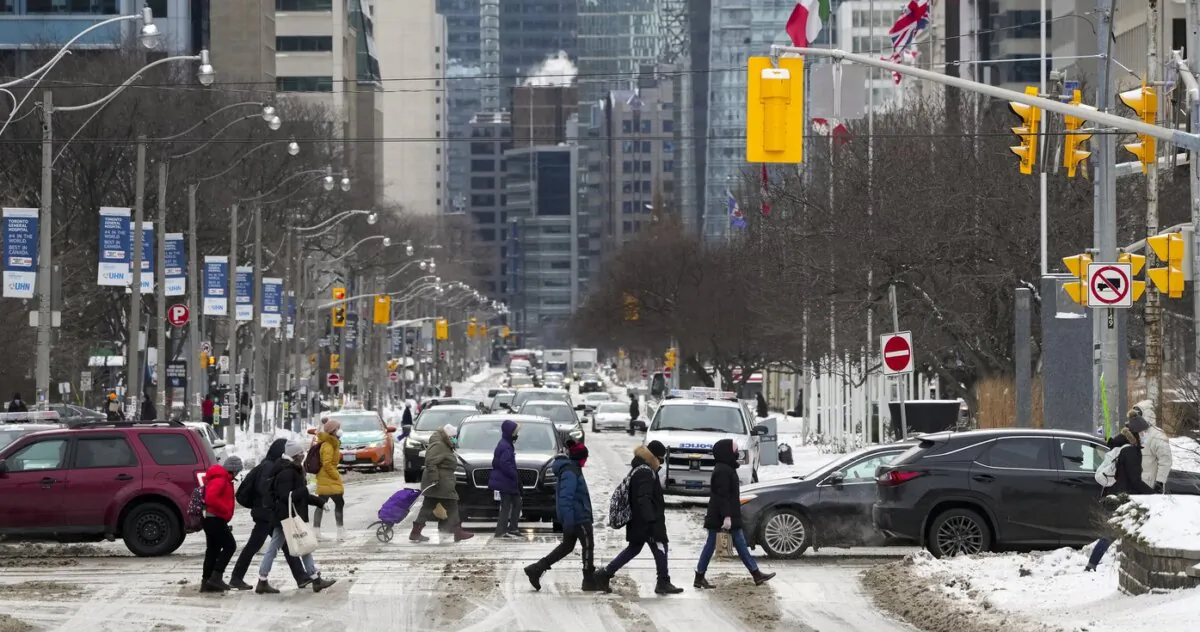 Pedestrians cross a street in Toronto on Feb. 4, 2022. (The Canadian Press/Nathan Denette)
