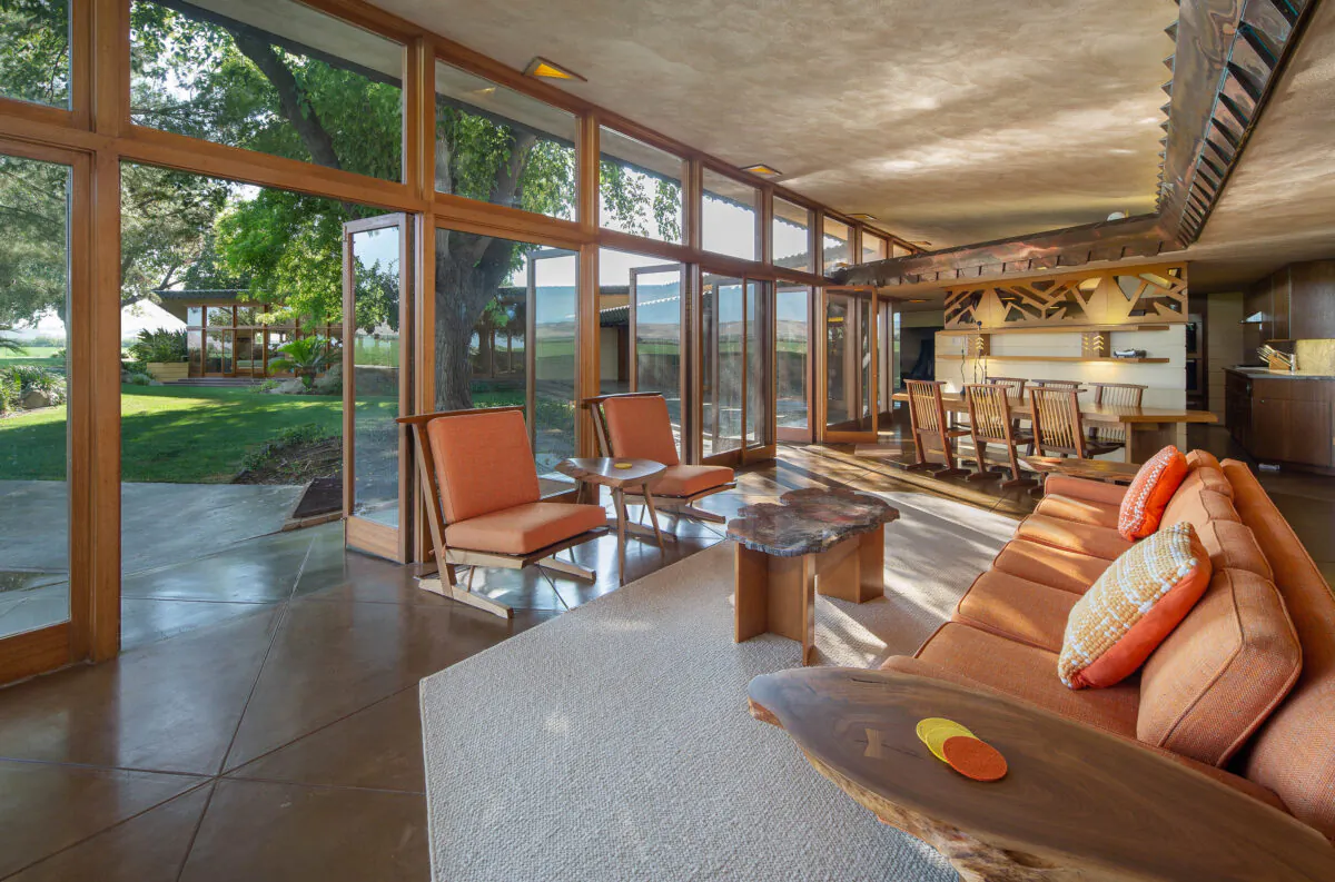 The airy living room and adjacent dining area both have relaxing views of the grounds, and are decorated with Wright-designed furniture. (Courtesy of Crosby Doe)