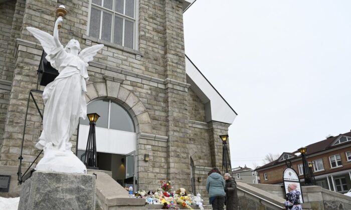 People gather on the steps of the church near a memorial for the victims in Amqui, Que., on March 14, 2023. (The Canadian Press/Jacques Boissinot) 