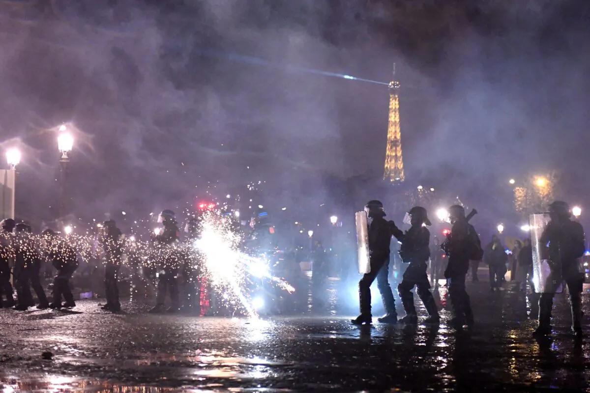 A protester shoots a firework at police officers, with the Eiffel tower seen in the background, during a demonstration on Place de la Concorde in Paris on March 17, 2023 (JULIEN DE ROSA/AFP via Getty Images)