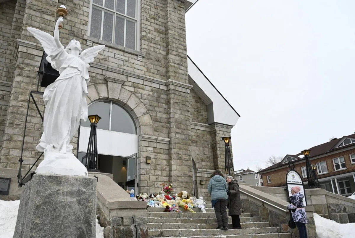 People gather among tributes left on the steps of the church in Amqui., Que., Mar. 14, 2023 in Amqui, Que. (The Canadian Press/Jacques Boissinot)