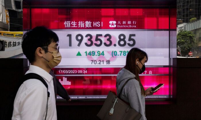 Pedestrians pass the Dah Sing Bank's electronic screen in Hong Kong, on March 17, 2023. (Louise Delmotte/AP Photo)