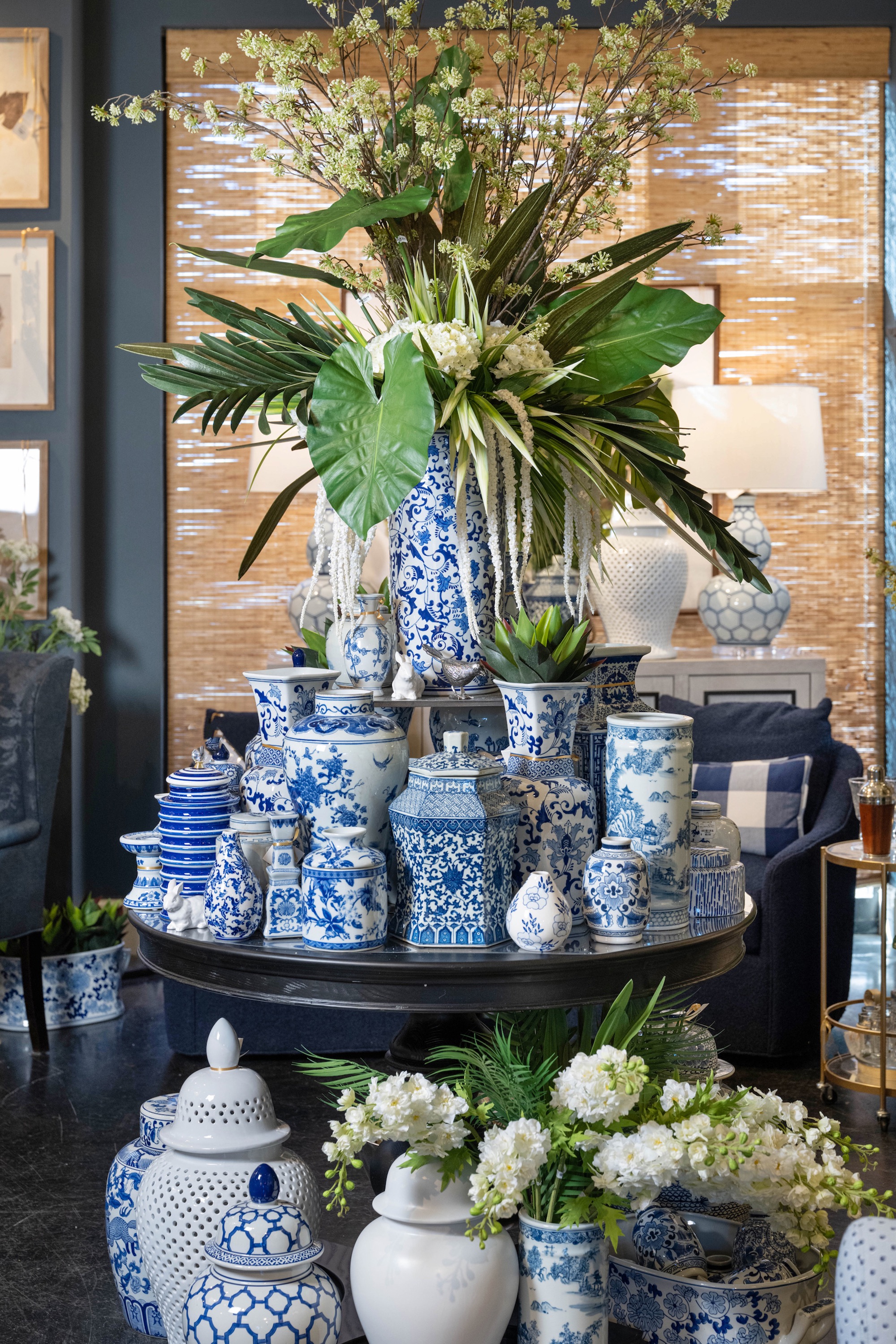 In this display, tulips, hydrangeas and drooping floral stems are the monochromatic base from which tropical greenery bursts. Monstera leaves and spiky palm fronds are mixed throughout, providing visual interest on all sides of the piece. 