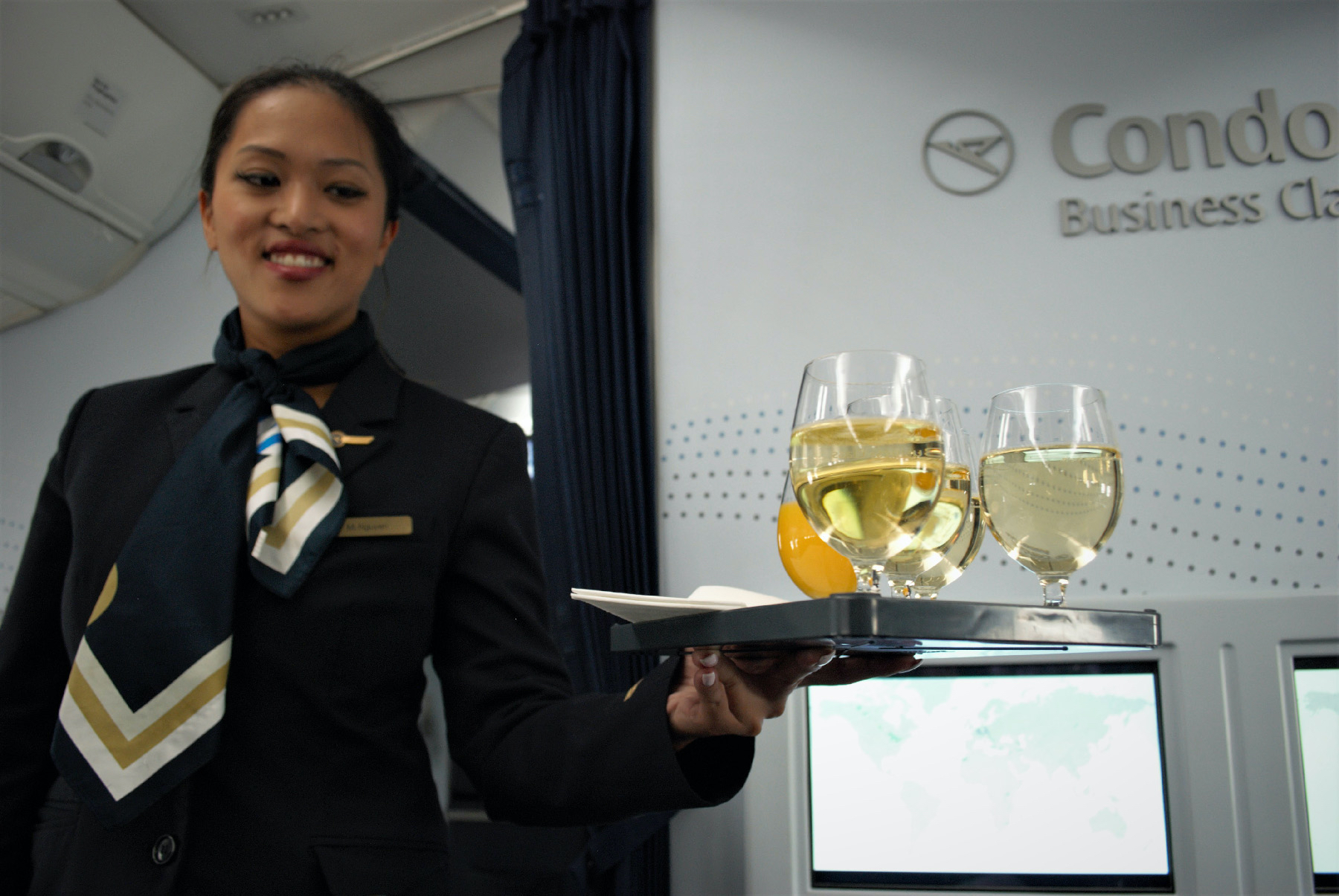 A flight attendant on Condor Airlines offers beverages to passengers en route from Frankfurt, Germany, to Los Angeles.