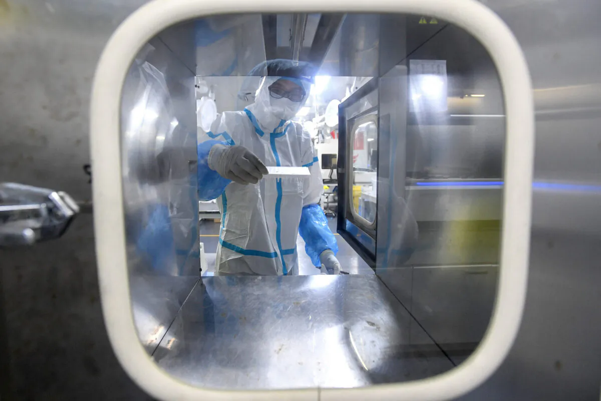 A laboratory technician wearing personal protective equipment (PPE) works on samples to be tested for the Covid-19 coronavirus at the Fire Eye laboratory, a Covid-19 testing facility, in Wuhan in China's central Hubei province early on Aug. 5, 2021. (STR/AFP via Getty Images)