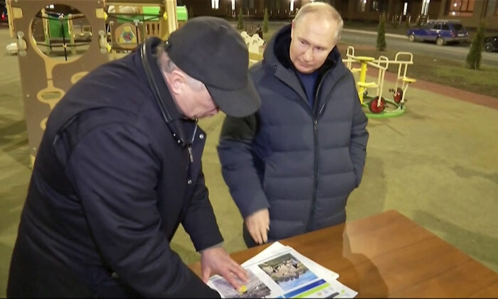 Russia's President Vladimir Putin (R) gestures while speaking with Deputy Prime Minister Marat Khusnullin as they look at reconstruction illustrations while he visits the Russia-annexed city of Mariupol late on March 18, 2023. (Pool/AFP via Getty Images)