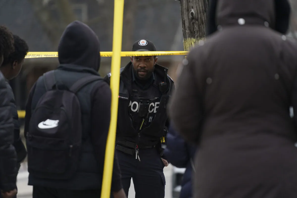 A police officer speaks to students at the scene of a shooting at Weston Collegiate Institute high school in Toronto on Feb. 16, 2023. (Arlyn McAdorey/The Canadian Press)