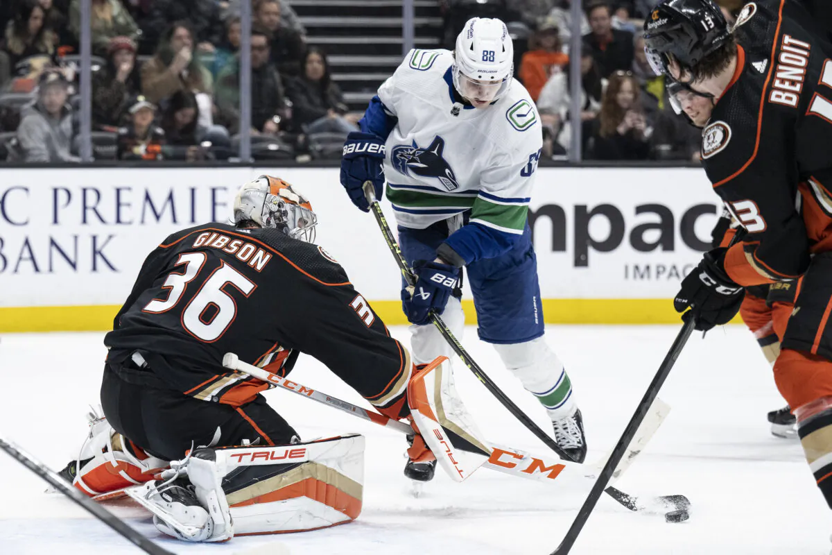 Anaheim Ducks goaltender John Gibson (36) pokes the puck away from Vancouver Canucks center Nils Aman (88) during the second period of an NHL hockey game in Anaheim, Calif., on March 19, 2023. (Kyusung Gong/AP Photo)