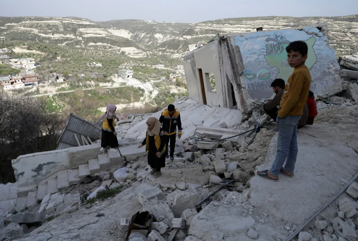 Salam Mahmoud, a volunteer at the Syria Civil Defence (White Helmets), walks with other volunteers on the rubble of a building, that was damaged by last month's devastating earthquake, in rebel-held al-Maland village, in Idlib province, Syria, on March 5, 2023. (Khalil Ashawi/Reuters)