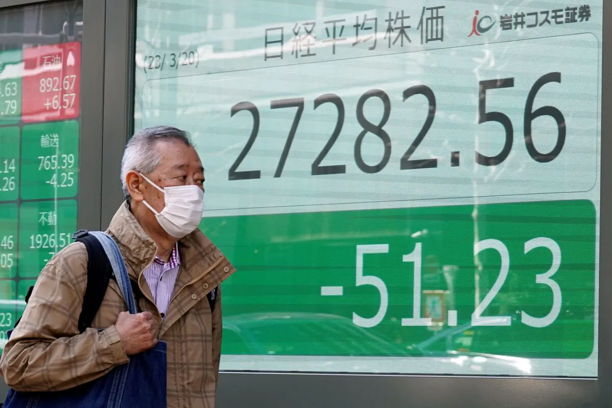A person walks in front of an electronic stock board showing Japan's Nikkei 225 index at a securities firm in Tokyo on March 20, 2023. (Eugene Hoshiko/AP Photo)