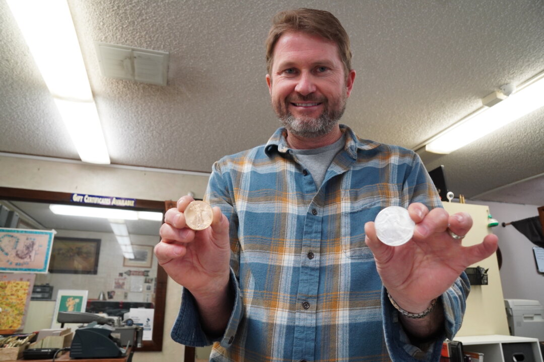 Gabe Wright, co-owner of Coin Heaven in Cottonwood, Ariz., holds gold and silver coins, two of the hottest selling items on March 20, 2023. (Allan Stein/The Epoch Times)