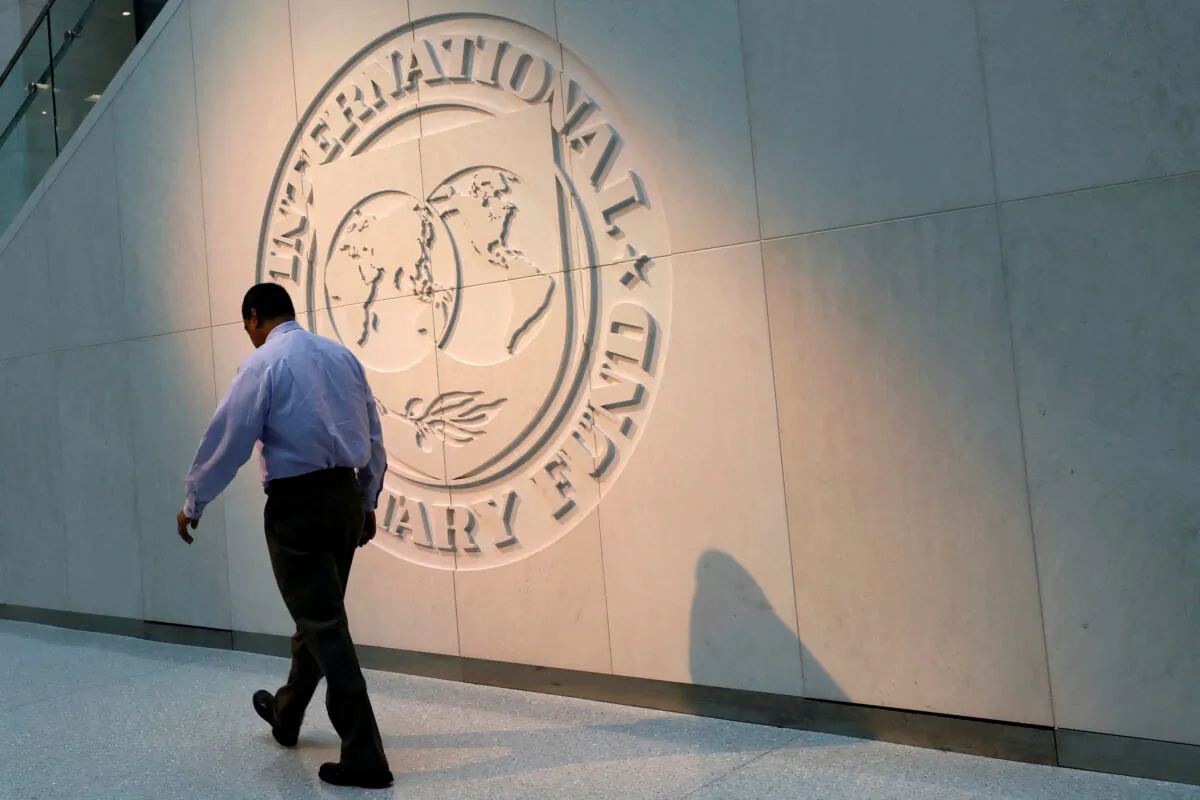 A man walks past the International Monetary Fund (IMF) logo at its headquarters in Washington on May 10, 2018. (Yuri Gripas/Reuters)