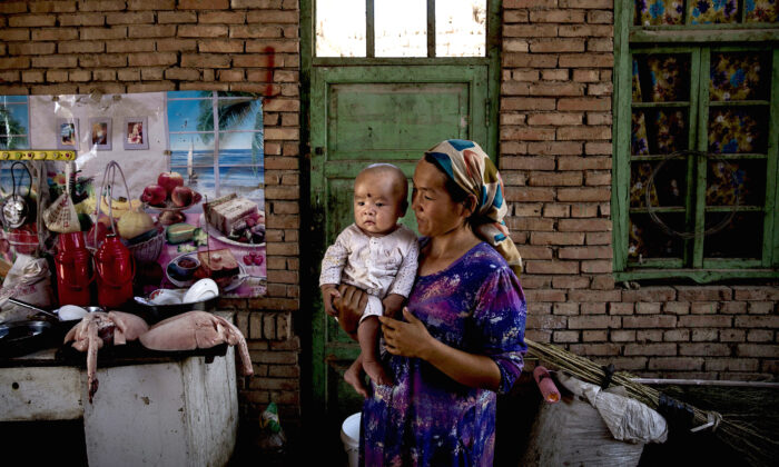 A Uyghur woman holds a child in her home as they prepare food during the Corban Festival in Turpan County, on Sept. 12, 2016. (Kevin Frayer/Getty Images)