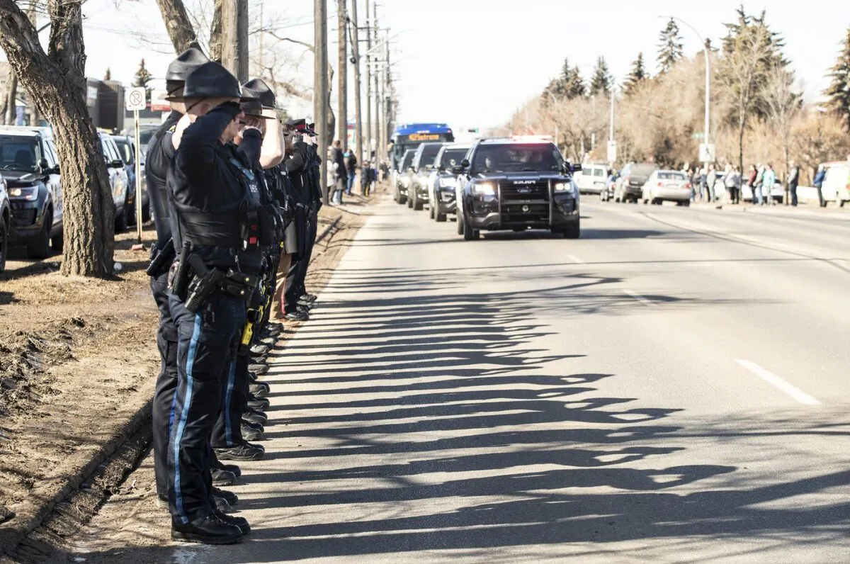 Police salute at the procession for the bodies of constables Travis Jordan and Brett Ryan, in Edmonton on Mar. 21, 2023. (The Canadian Press/Jason Franson)
