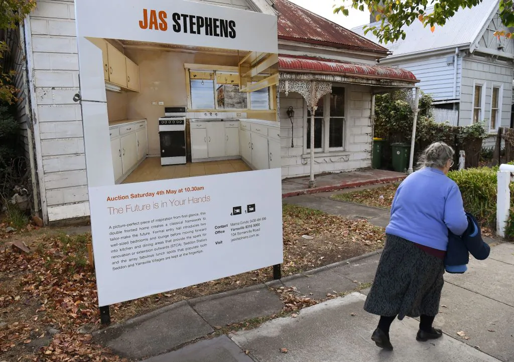 A woman walks past a real estate agent's sign advertising a house for auction in Melbourne on May 1, 2019. (Photo by William WEST / AFP via Getty Images)