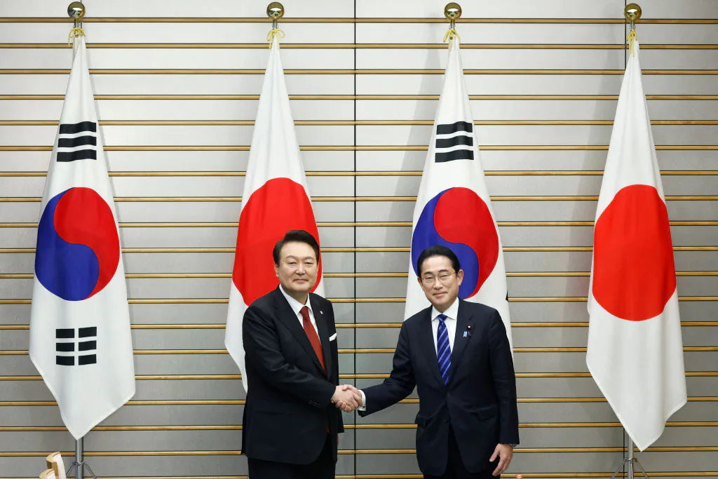 Yoon Suk Yeol, South Korea's president (L), and Fumio Kishida, Japan's prime minister, shake hands ahead of a summit meeting at the prime minister's official residence in Tokyo on March 16, 2023. (Kiyoshi Ota/Getty Images)