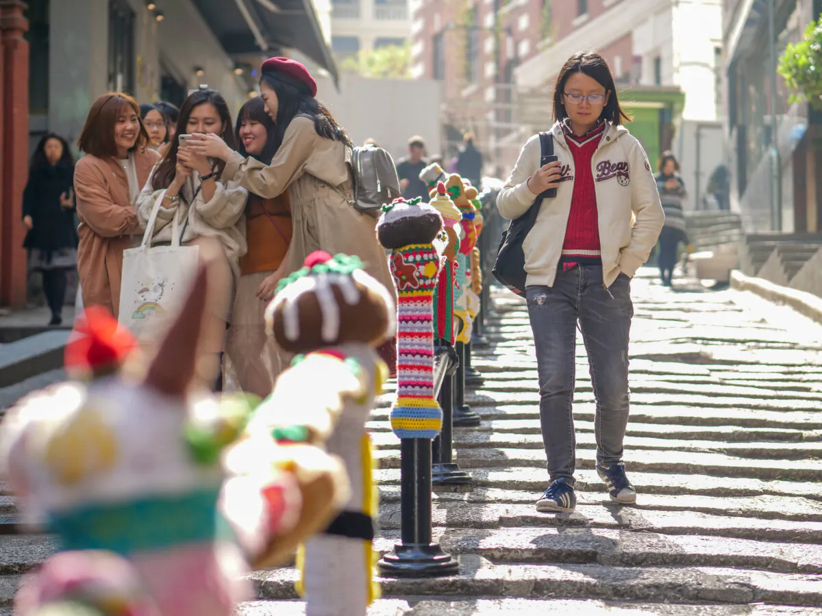 The contrast between the loneliness and happiness of young people on the street in Sheung Wan, Hong Kong, in January 2019 is stark. (David Pan/The Epoch Times)