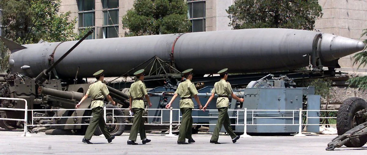 Four People's Liberation Army (PLA) soldiers march past an old Chinese medium range ballistic missile on display in front of Beijing's military museum, on July 26, 1999. (Stephen Shaver /AFP via Getty Images)