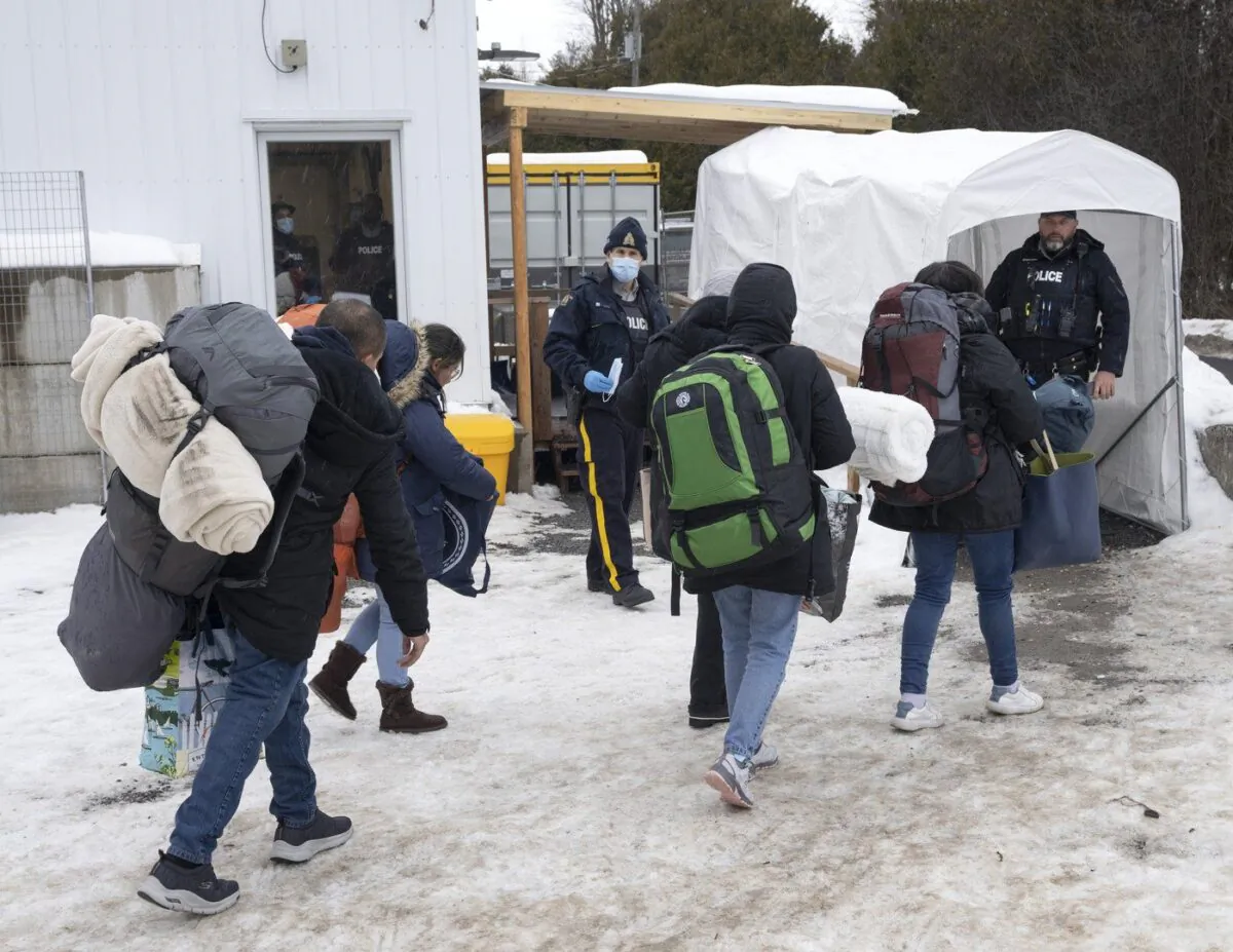A family of asylum-seekers from Colombia is met by RCMP officers after crossing the Canada-U.S. border at Roxham Road, Quebec, into Canada on Feb. 9, 2023. (Ryan Remiorz/The Canadian Press)