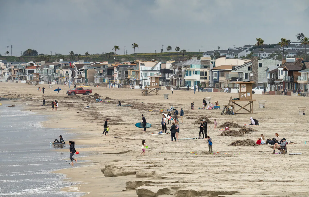 Surfers and beachgoers take advantage of a gap during local storm systems in Newport Beach, Calif., on March 23, 2023. (John Fredricks/The Epoch Times)