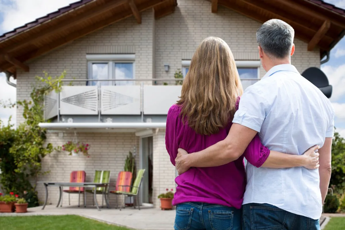 A couple standing in front of their house. (Shutterstock)