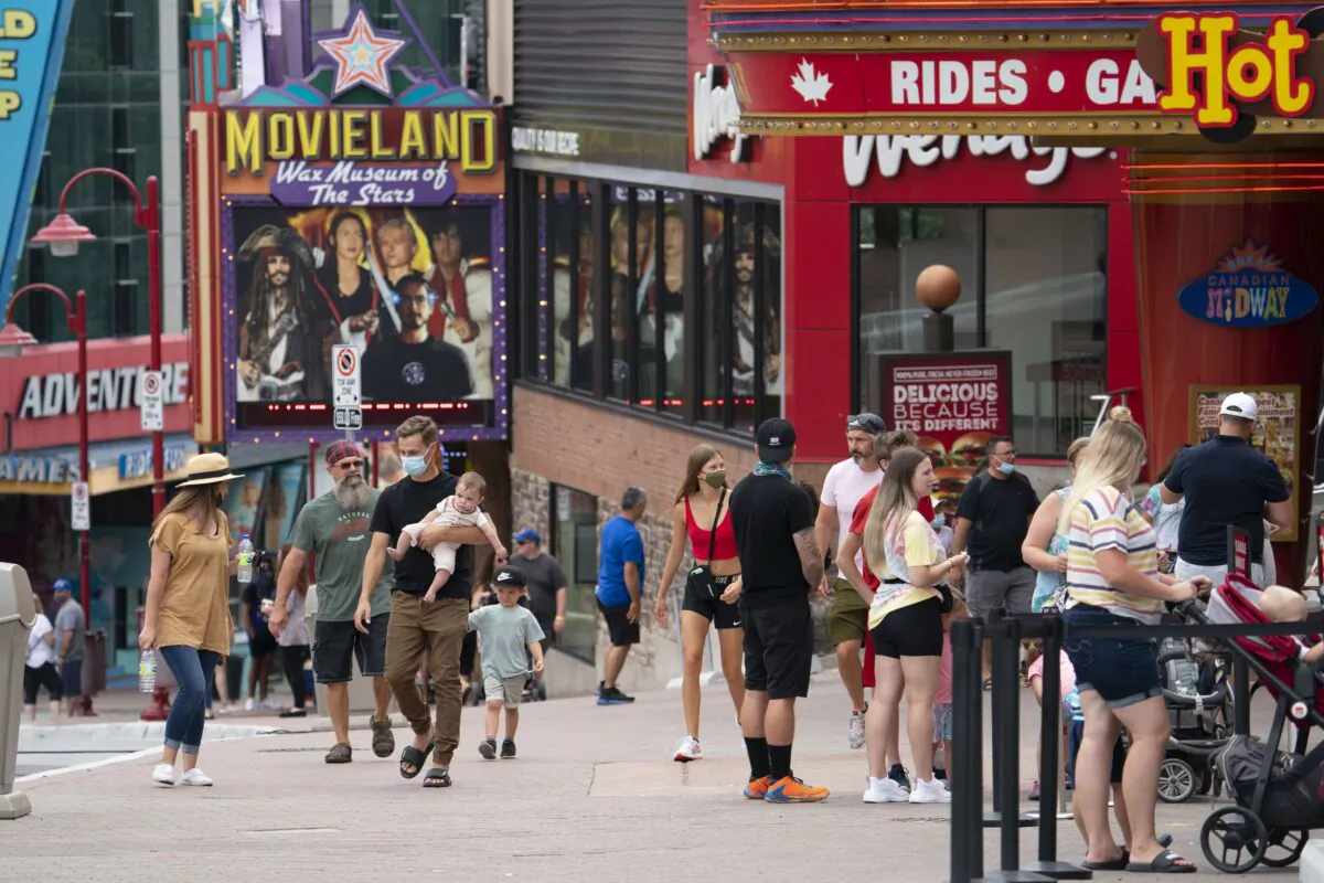 People on a street in a tourist area of Niagara Falls, Ont., July 16, 2021. (The Canadian Press/Peter Power)