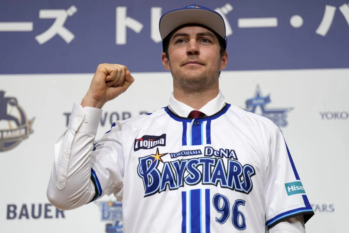 Trevor Bauer with his new uniform and cap of Yokohama DeNA BayStars poses for photographers during a photo session of the news conference in Yokohama, near Tokyo, on March 24, 2023. (Eugene Hoshiko/AP Photo)
