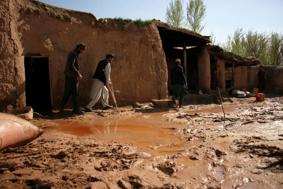 A disabled man (C) walks inside his damaged home after heavy rain in the Zari District of Balkh Province, in northern Afghanistan, on March 25, 2023. (AP Photo)