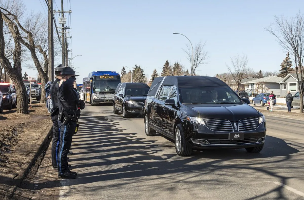 Police salute during a procession to a funeral home for Const. Travis Jordan and Const. Brett Ryan in Edmonton on March 21, 2023. (The Canadian Press/Jason Franson)