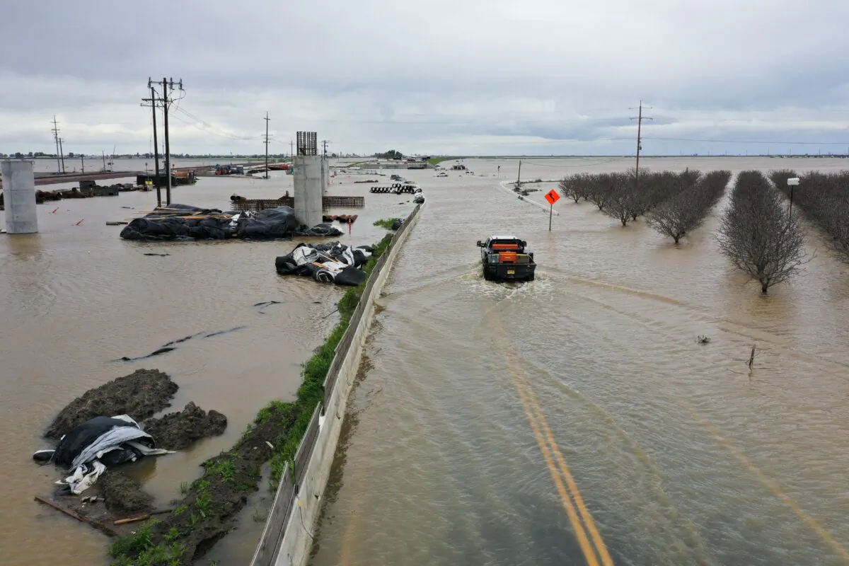 An aerial image shows a truck as it drives across a flooded road past Central Valley farmland along the Tule River in Tulare County during a storm near Corcoran, Calif., on March 21, 2023. (Patrick T. Fallon/AFP via Getty Images)