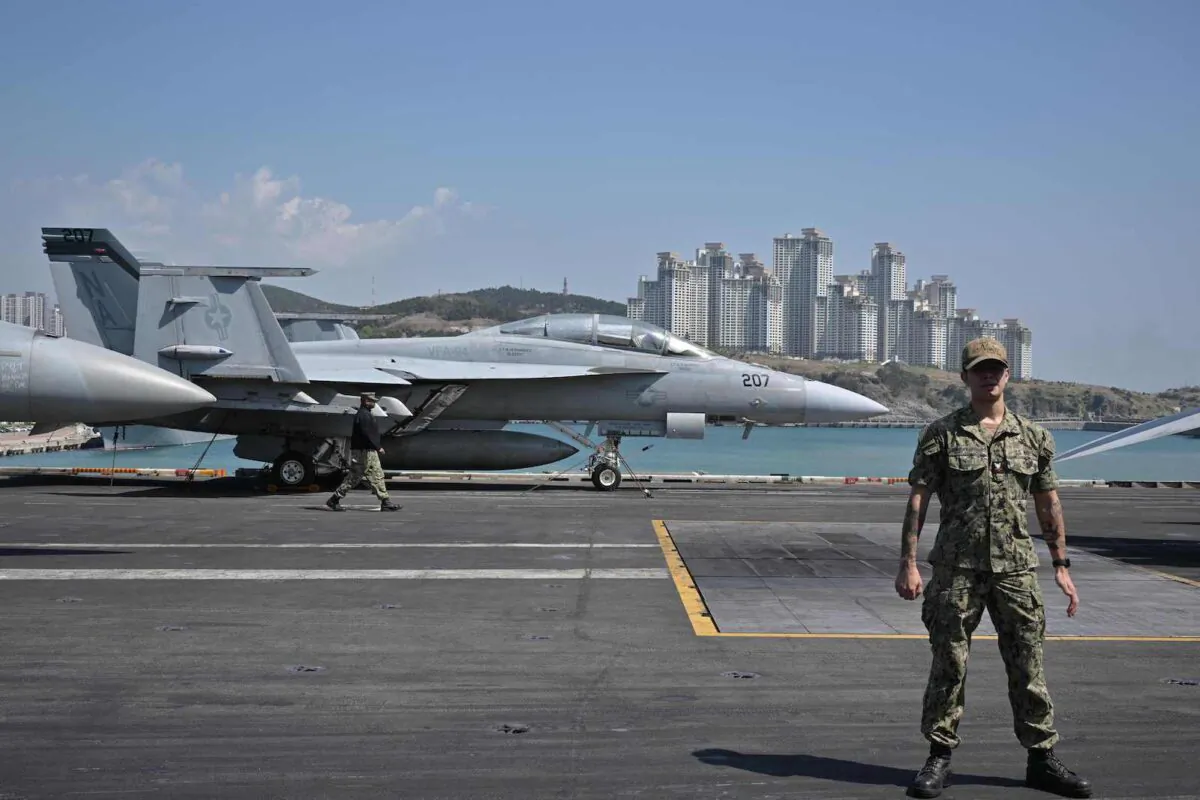 A U.S. Navy sailor stands guard in front of a F/A-18F Super Hornet aboard the USS Nimitz during its port visit to Busan on March 28, 2023. (Anthony Wallace/AFP via Getty Images)
