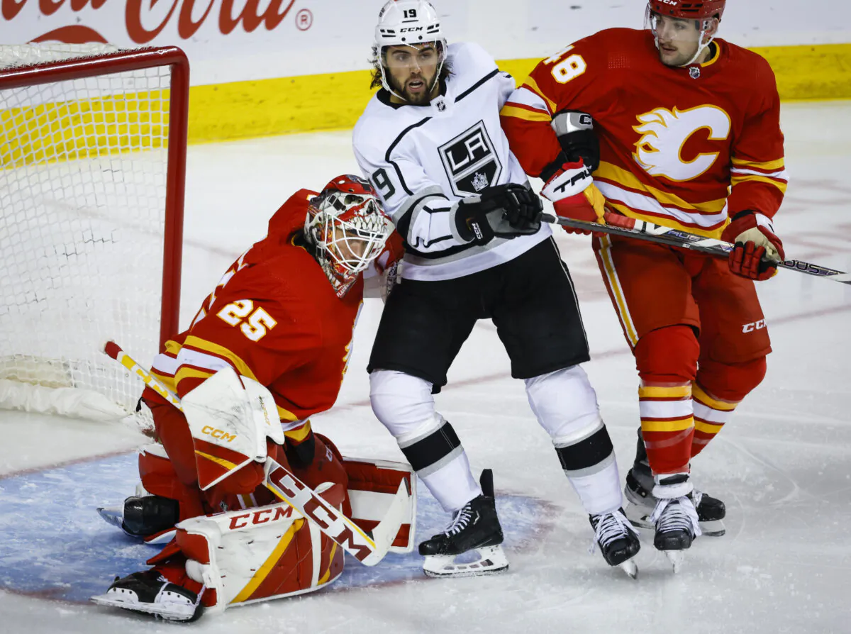 Los Angeles Kings forward Alex Iafallo, center, is checked by Calgary Flames defenseman Dennis Gilbert, right, into goalie Jacob Markstrom during the second period of an NHL hockey game in Calgary, Alberta on March 28, 2023. (Jeff McIntosh/The Canadian Press via AP)