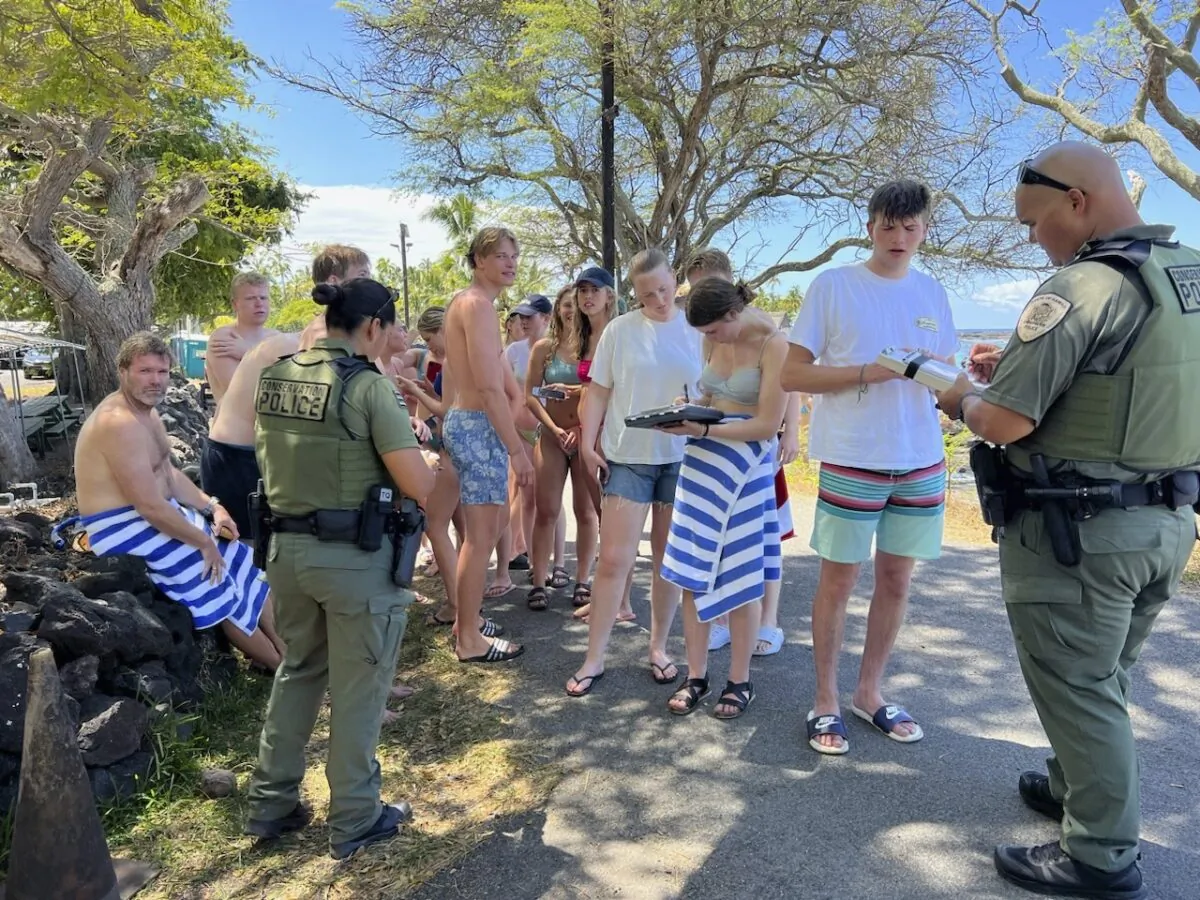 Department enforcement officers speak to swimmers in Honaunau, Hawaii, on March 26, 2023, after the swimmers allegedly harassed a pod of wild spinner dolphins. (Hawaii Department of Land and Natural Resources via AP)