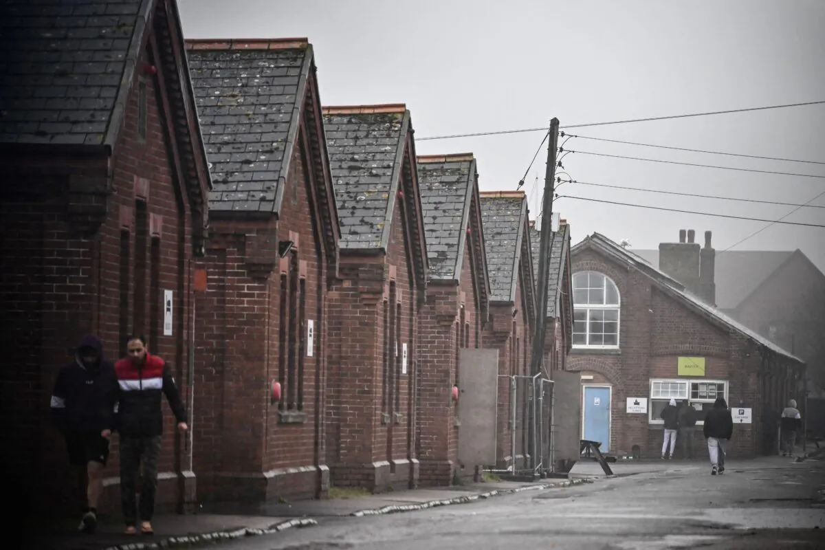 Residents of Napier Barracks, a former military barracks that is being used to house illegal immigrants, walk under the rain among the buildings, in Folkestone, southeast England, on March 9, 2023. (Ben Stansall/AFP via Getty Images)