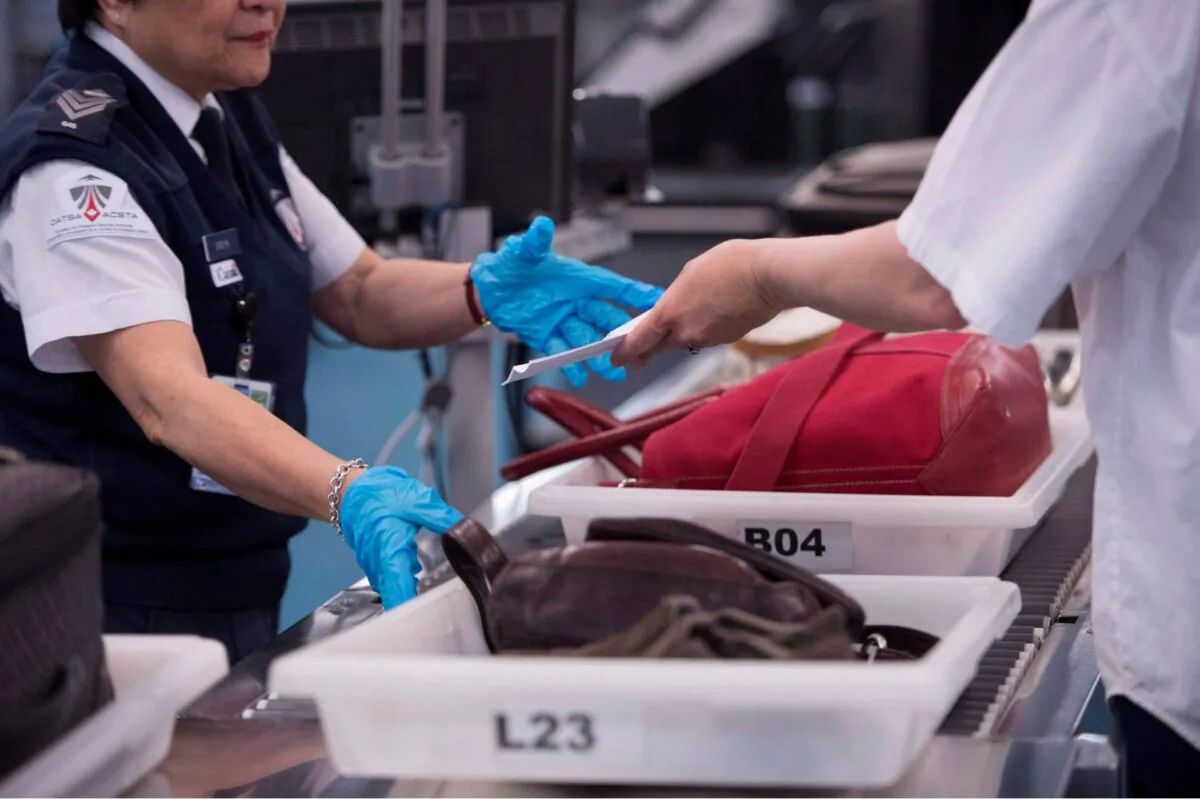 An employee performs security checks of passengers and their carry-on luggage at Vancouver International Airport in Richmond, B.C., in a file photo. (Jonathan Hayward/The Canadian Press)