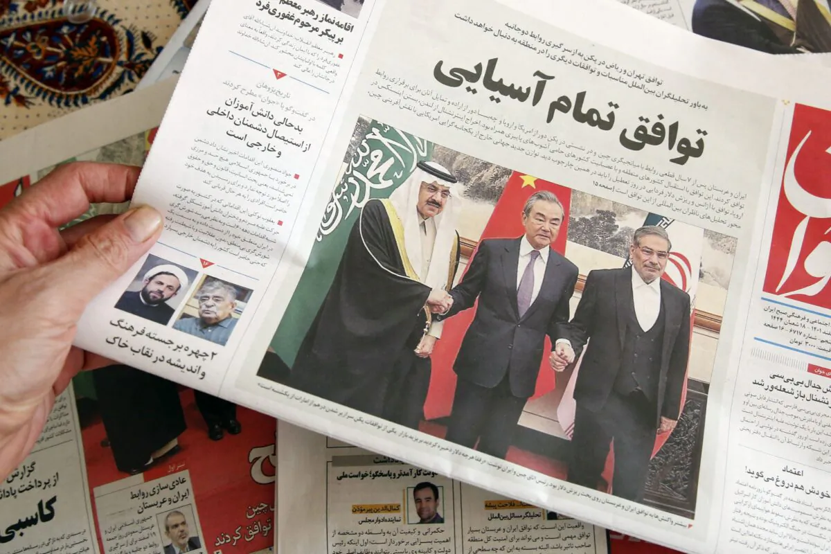 A man holds a local newspaper reporting on the China-brokered deal between Iran and Saudi Arabia to restore ties, in the Iranian capital Tehran on March 11, 2023. (Atta Kenare/AFP via Getty Images)