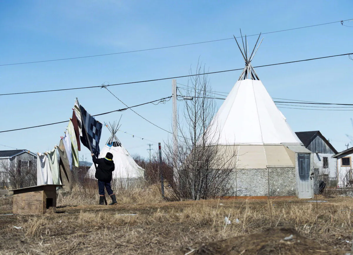 An indigenous women takes down laundry in the northern Ontario First Nations reserve in Attawapiskat, Ont., on April 19, 2016. (The Canadian Press/Nathan Denette)