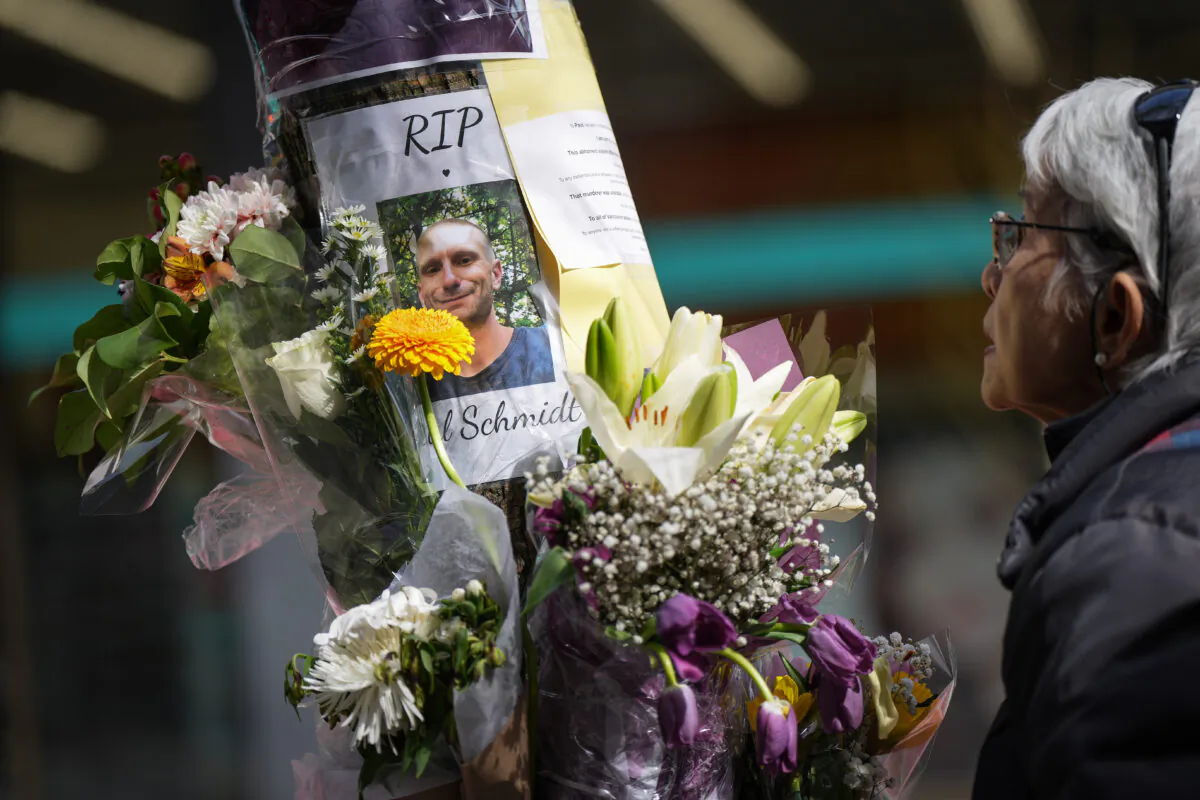 A woman pauses at a makeshift memorial for Paul Stanley Schmidt, 37, who died after being stabbed on Sunday outside a Starbucks in downtown Vancouver, on March 29, 2023. Vancouver police say Inderdeep Singh Gosal, 32, has been charged with second-degree murder and investigators do not believe the suspect and victim knew each other. (The Canadian Press/Darryl Dyck)