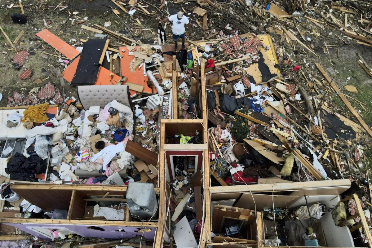 A man, top center, salvages a jacket as he looks over a tornado damaged home, in Rolling Fork, Miss., on March 26, 2023. (Julio Cortez/AP Photo)