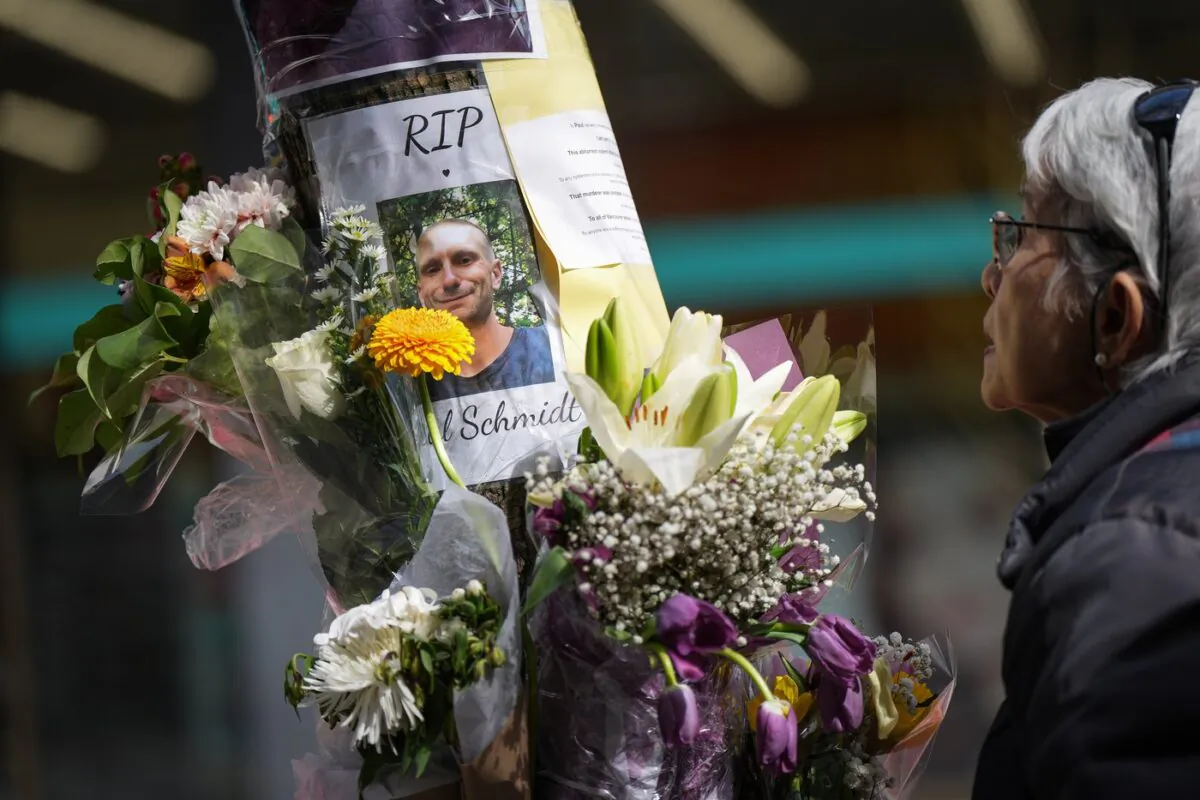 A woman pauses at a makeshift memorial for Paul Stanley Schmidt, 37, who died after being stabbed on Sunday outside a Starbucks in downtown Vancouver, on Wednesday, March 29, 2023. (The Canadian Press/Darryl Dyck)