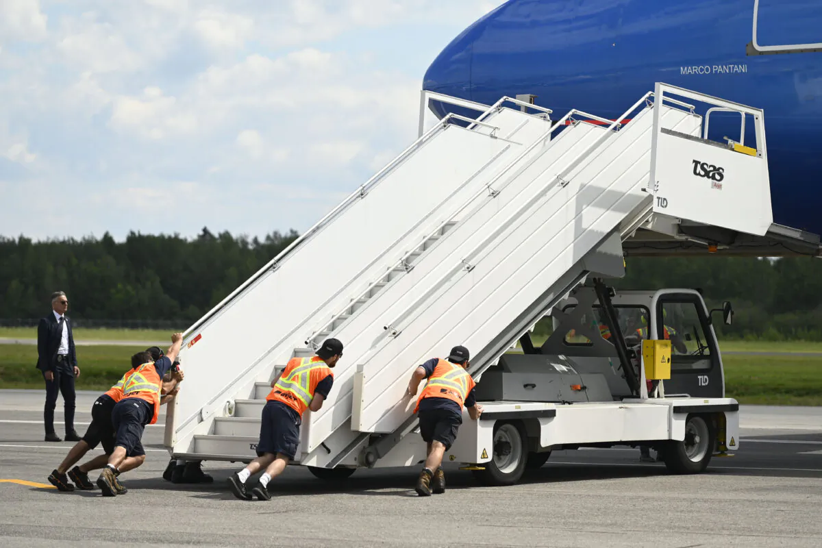 A file photo of airport workers pushing a ramp up to a plane in Quebec City on July 27, 2022. New child labour rules effective June 12, 2023, will apply to minors working at aiports and other federally regulated businesses in Canada. (Bernard Brault/The Canadian Press)