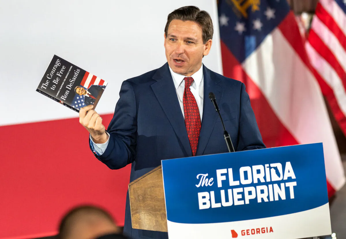Florida Gov. Ron DeSantis hawks his book at a book tour speech in Smyrna, Ga., on March 30, 2023. (Phil Mistry/The Epoch Times.)