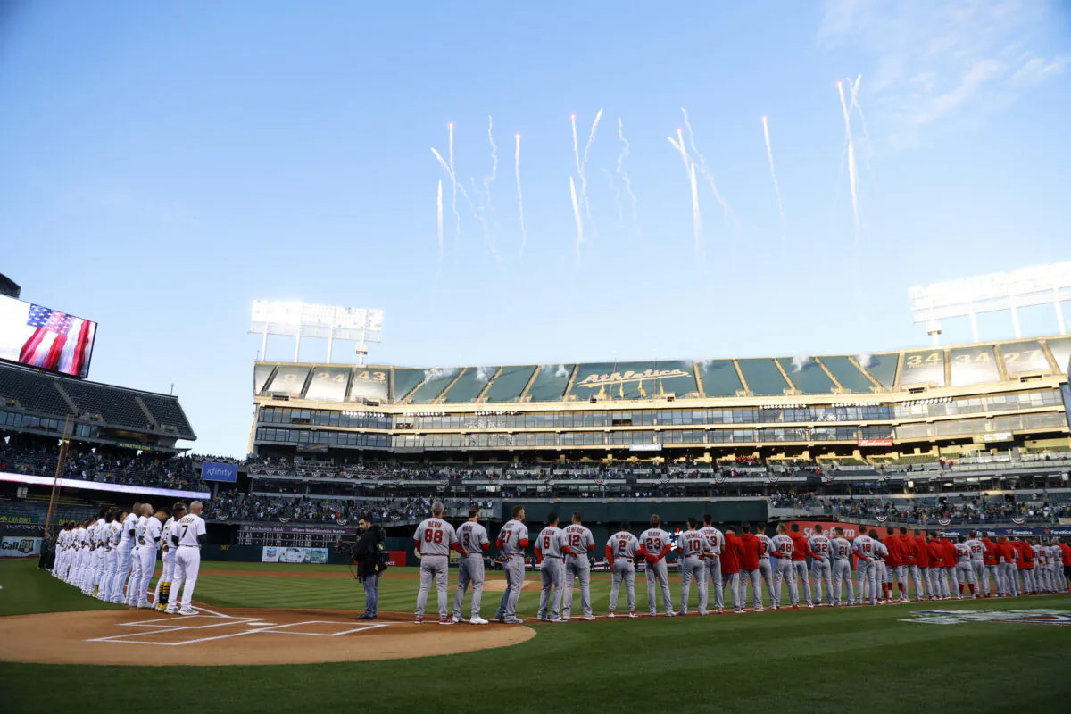 Oakland Athletics, left, and Los Angeles Angels players and coaches stand on the baselines before an opening day baseball game in Oakland on March 30, 2023. (Jed Jacobsohn/AP Photo)