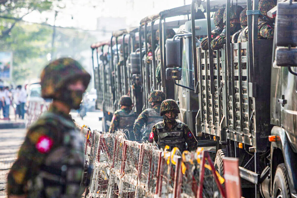 Soldiers stand next to military vehicles as people gather to protest against the military coup, in Yangon, Burma, on Feb. 15, 2021. (Stringer/Reuters)