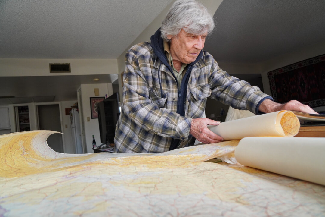 George Ilinsky of Phoenix, Ariz., goes over actual recovered maps used by the German Wehrmacht during World War II in Eastern Europe. (Allan Stein/The Epoch Times)