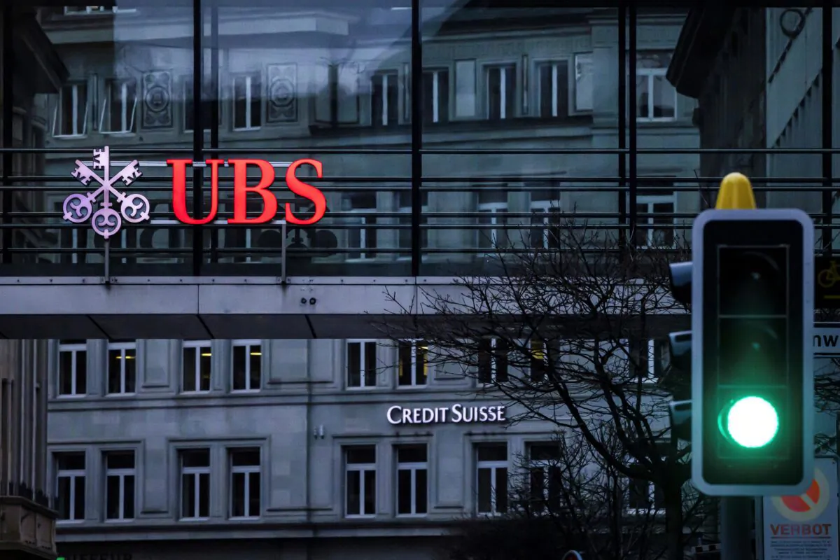 A traffic light signals green in front of the logos of the Swiss banks Credit Suisse and UBS in Zurich on March 19, 2023. (Michael Buholzer/Keystone via AP)