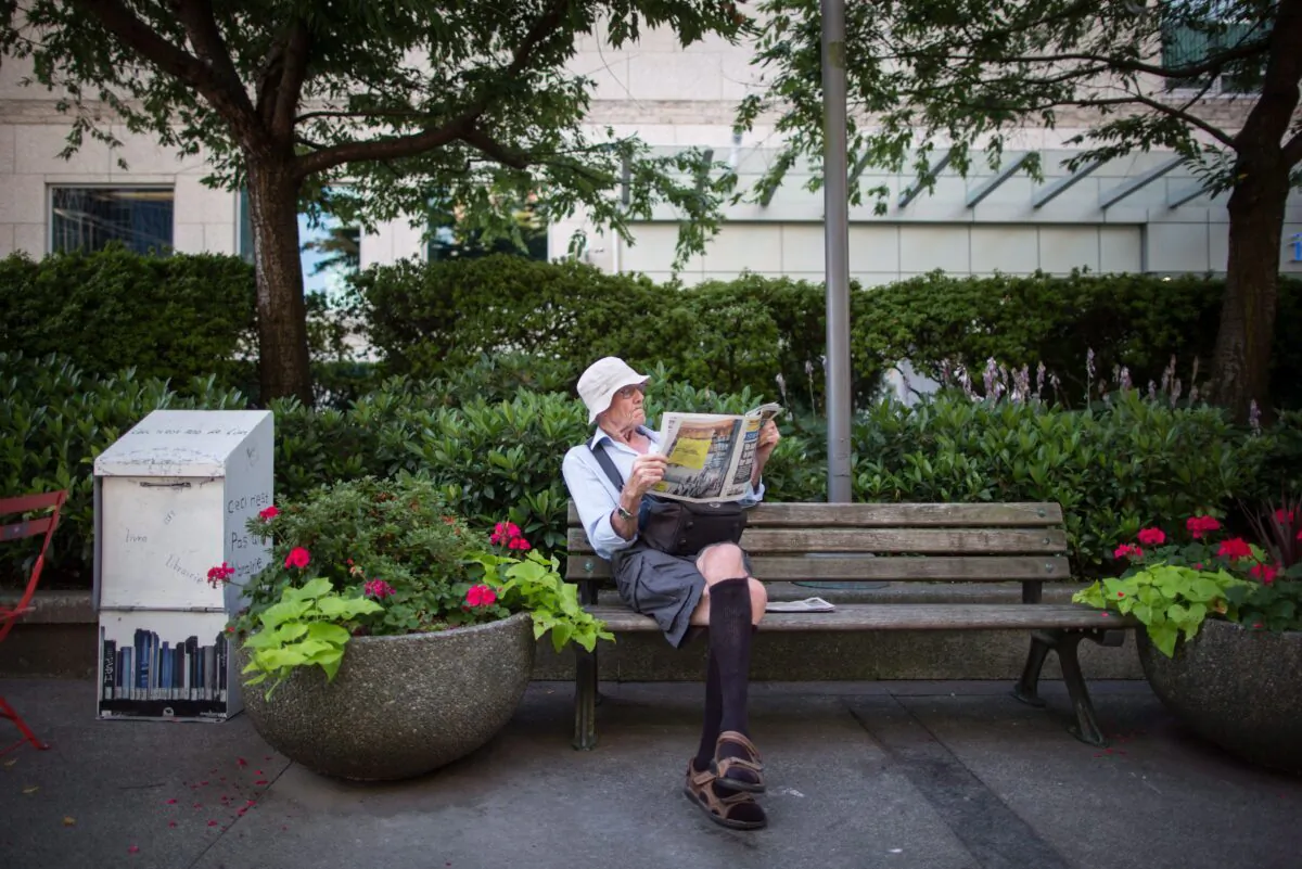 A man reads a newspaper while sitting on a park bench in downtown Vancouver in a file photo. (The Canadian Press/Darryl Dyck)