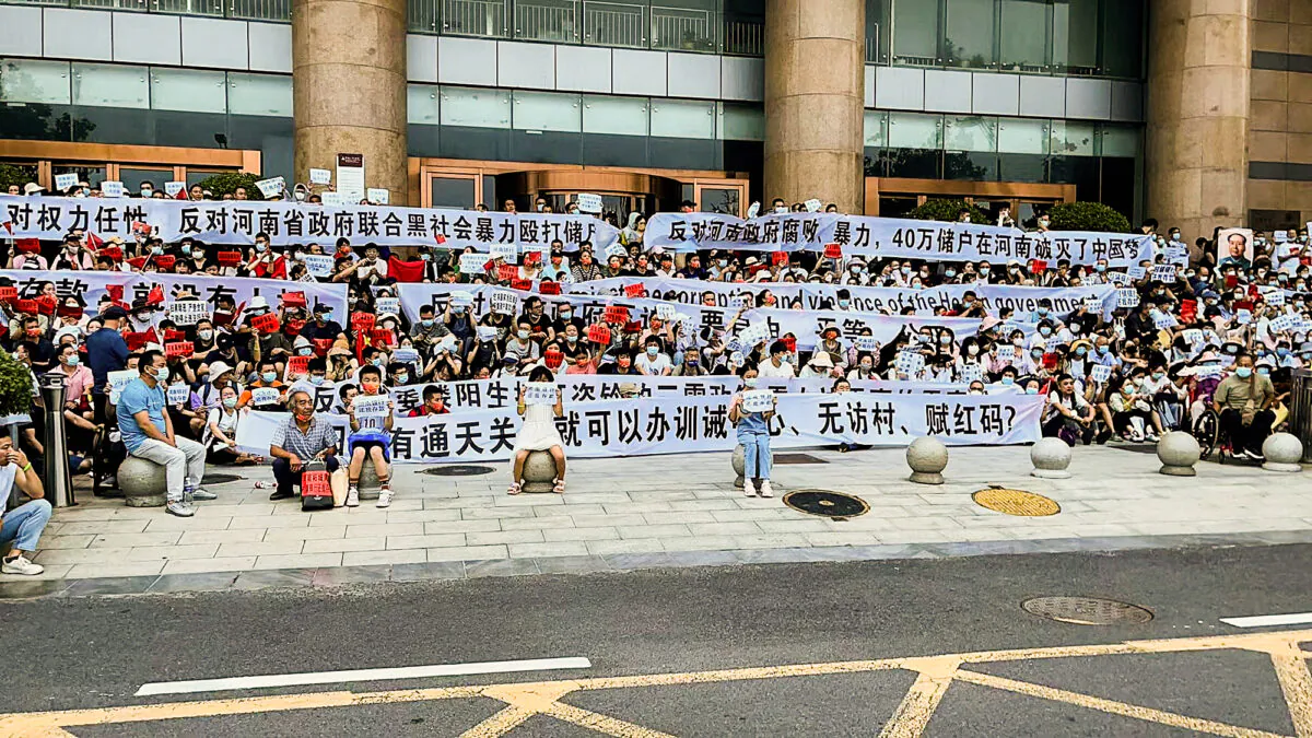 People hold banners and chant slogans during a protest at the entrance to a branch of China's central bank in Zhengzhou in central China's Henan Province, on July 10, 2022, when four rural banks in the Henan Province stopped allowing customers to withdraw cash since April 2022. (Yang/AP Photo)