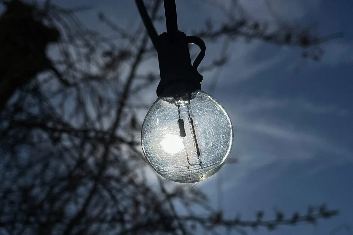 The sun shines behind a row of incandescent fairy lights on a restaurant terrace in Berlin's Kreuzberg district on March 16, 2023. (David Gannon/AFP via Getty Images)